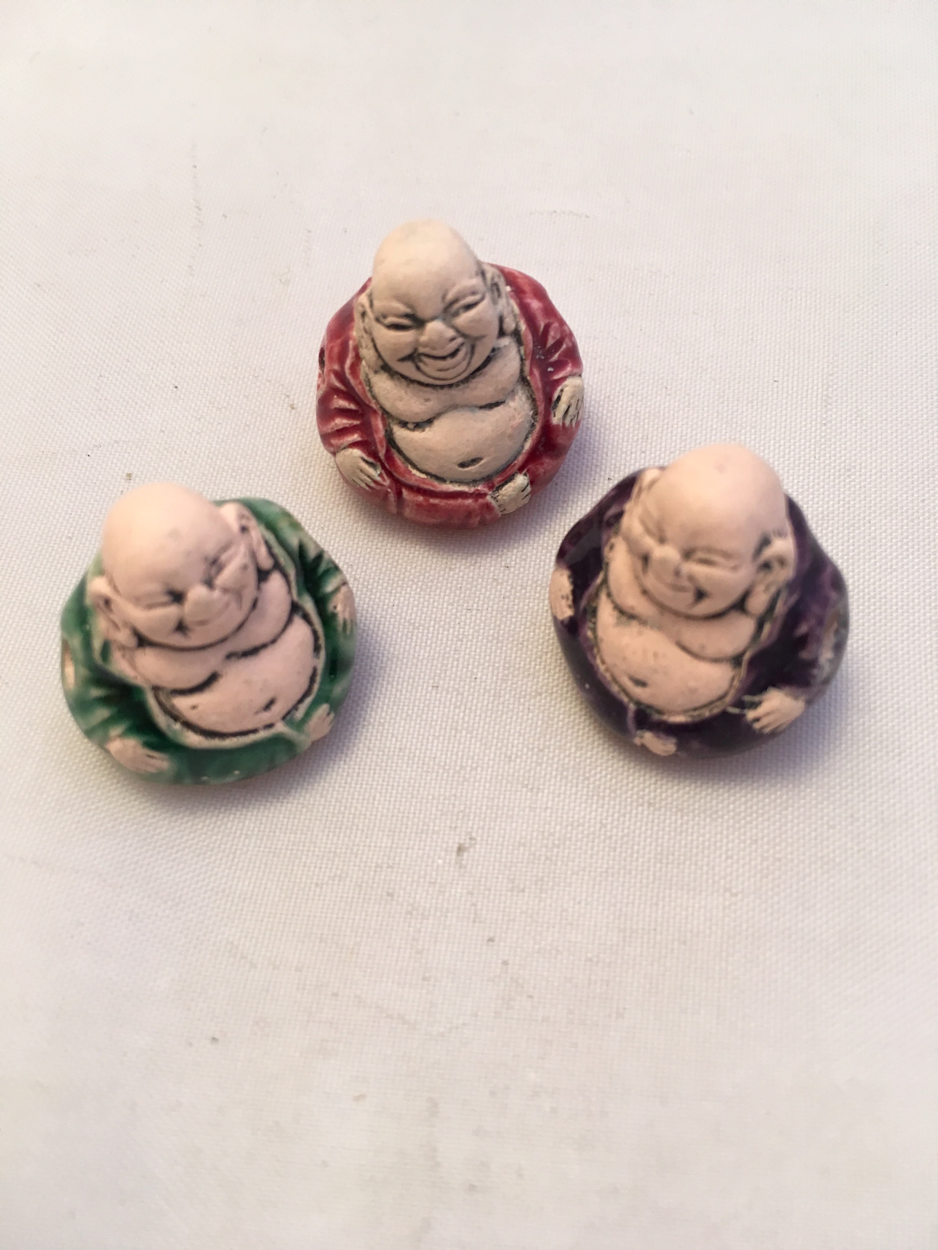 Three small ceramic buddhas sitting on a table.