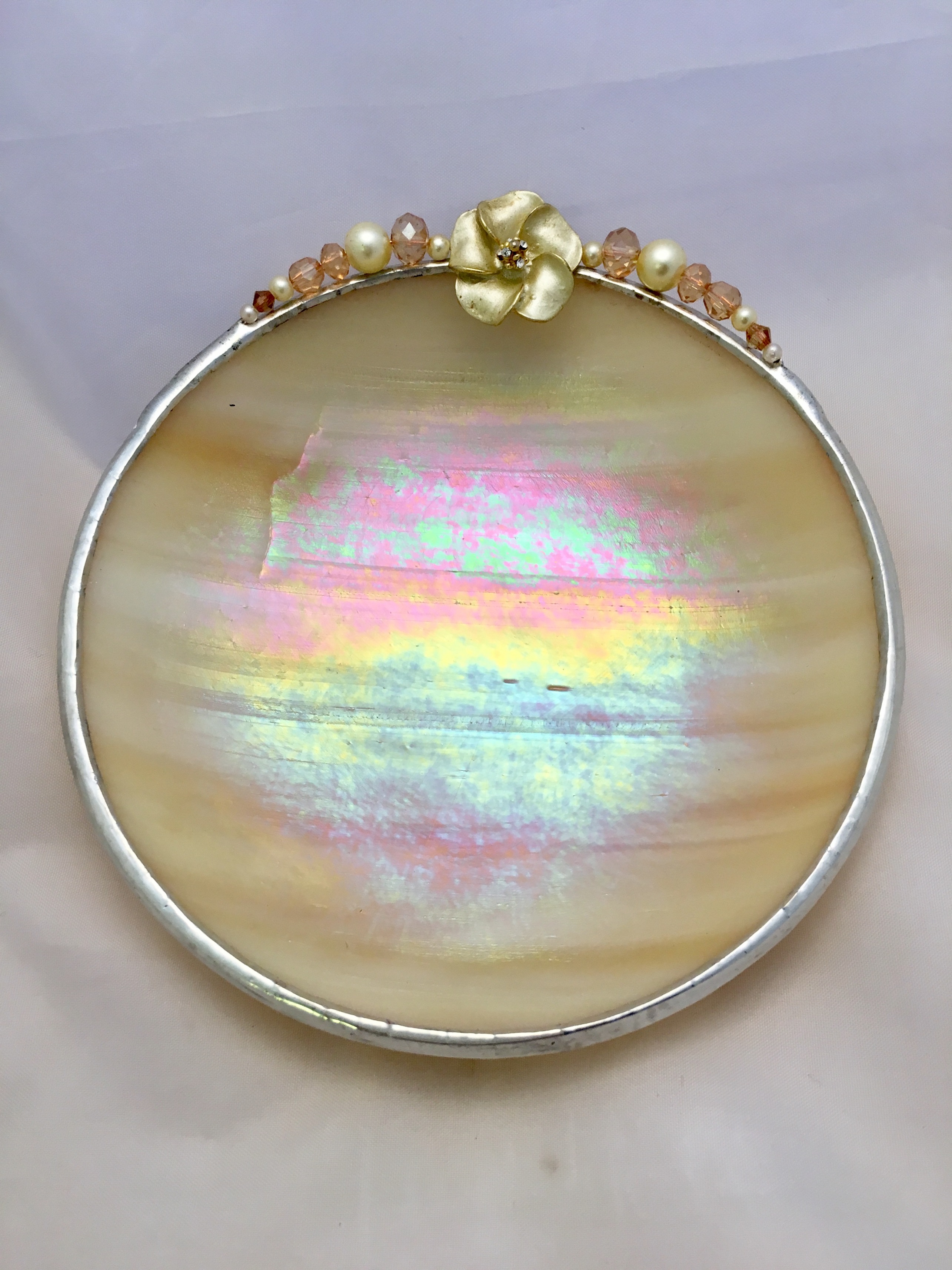 A round dish with iridescent finish and gold accents.