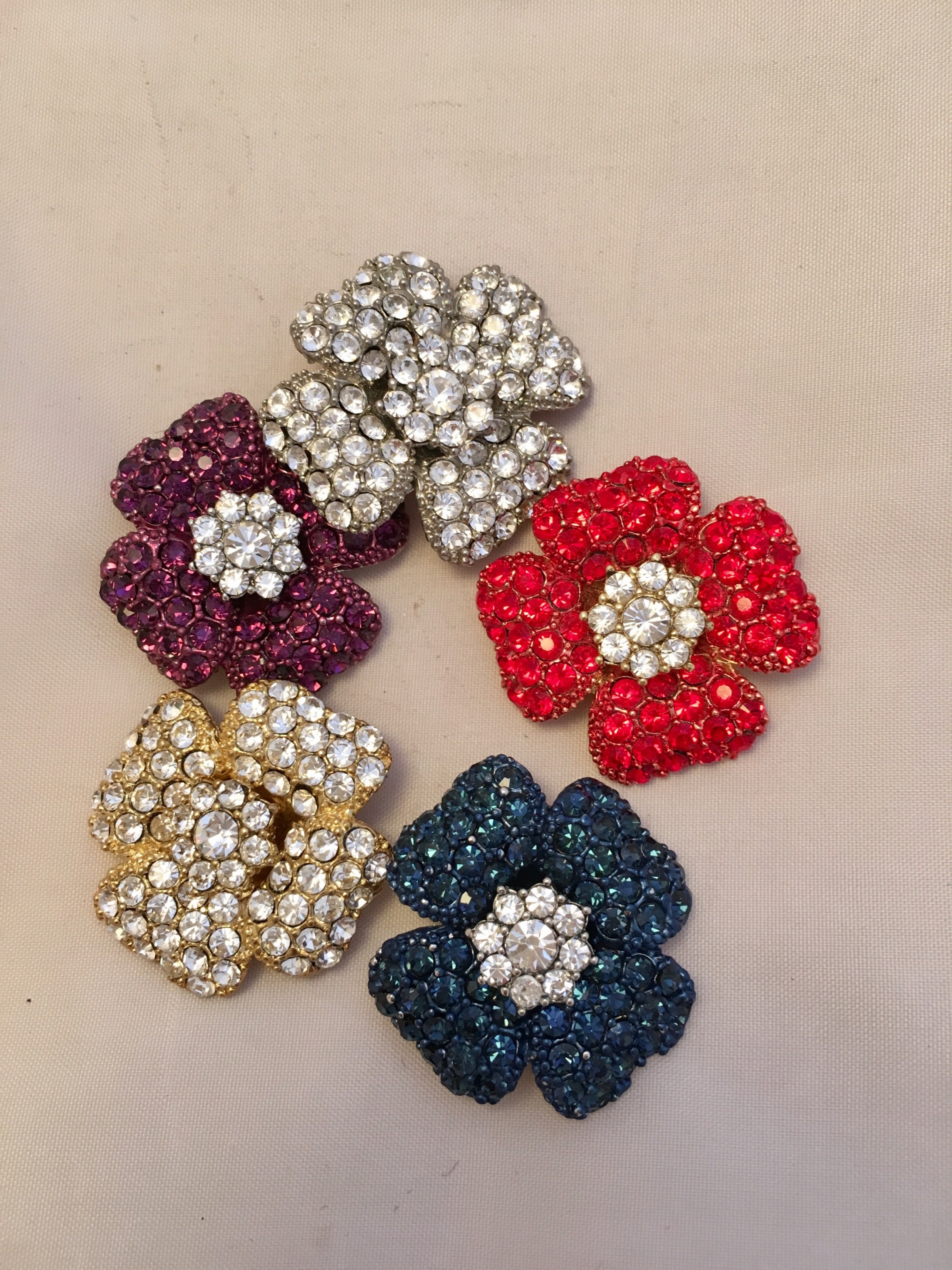 A group of five different colored flowers with rhinestones.