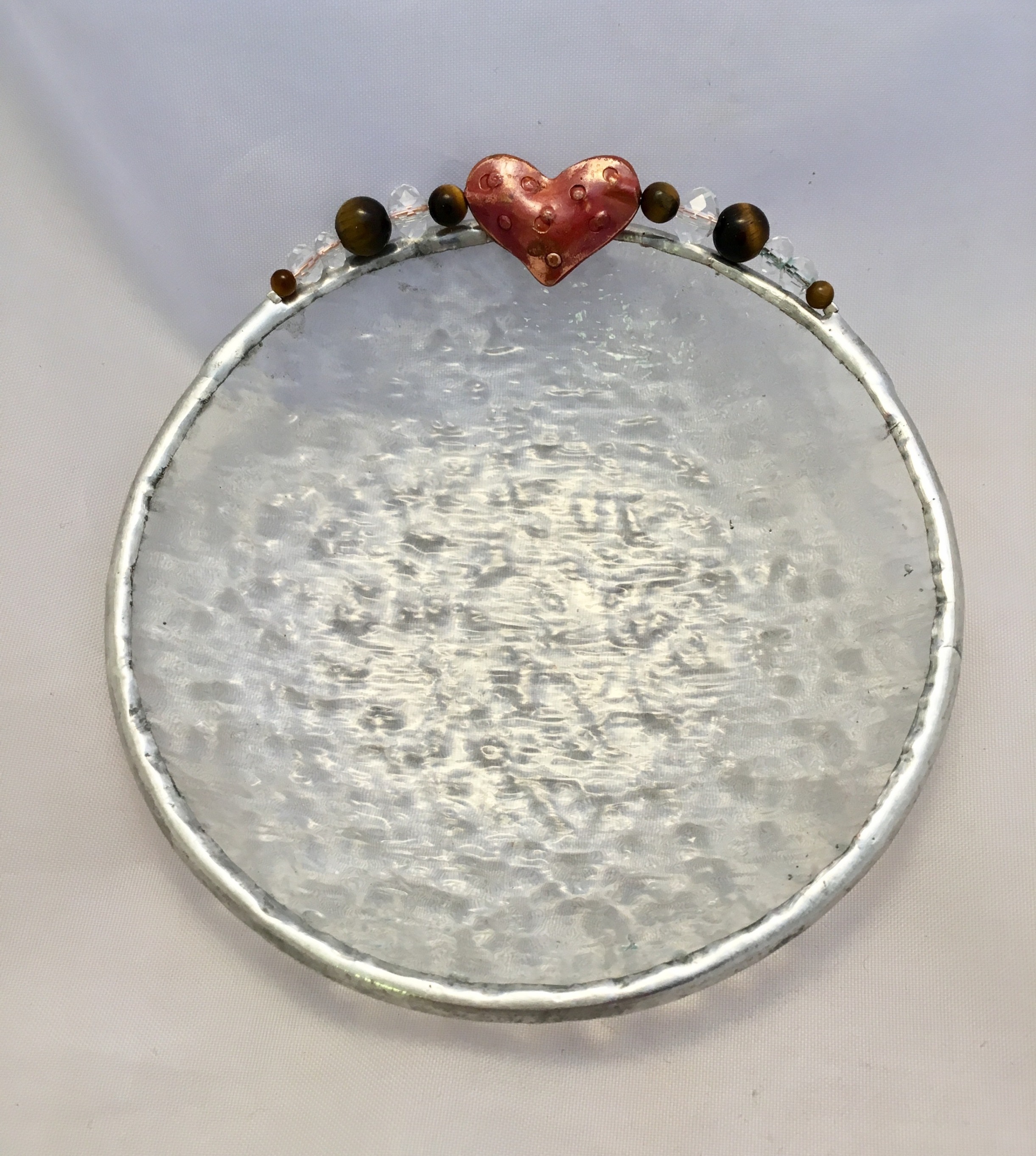 A round metal tray with a heart on top.