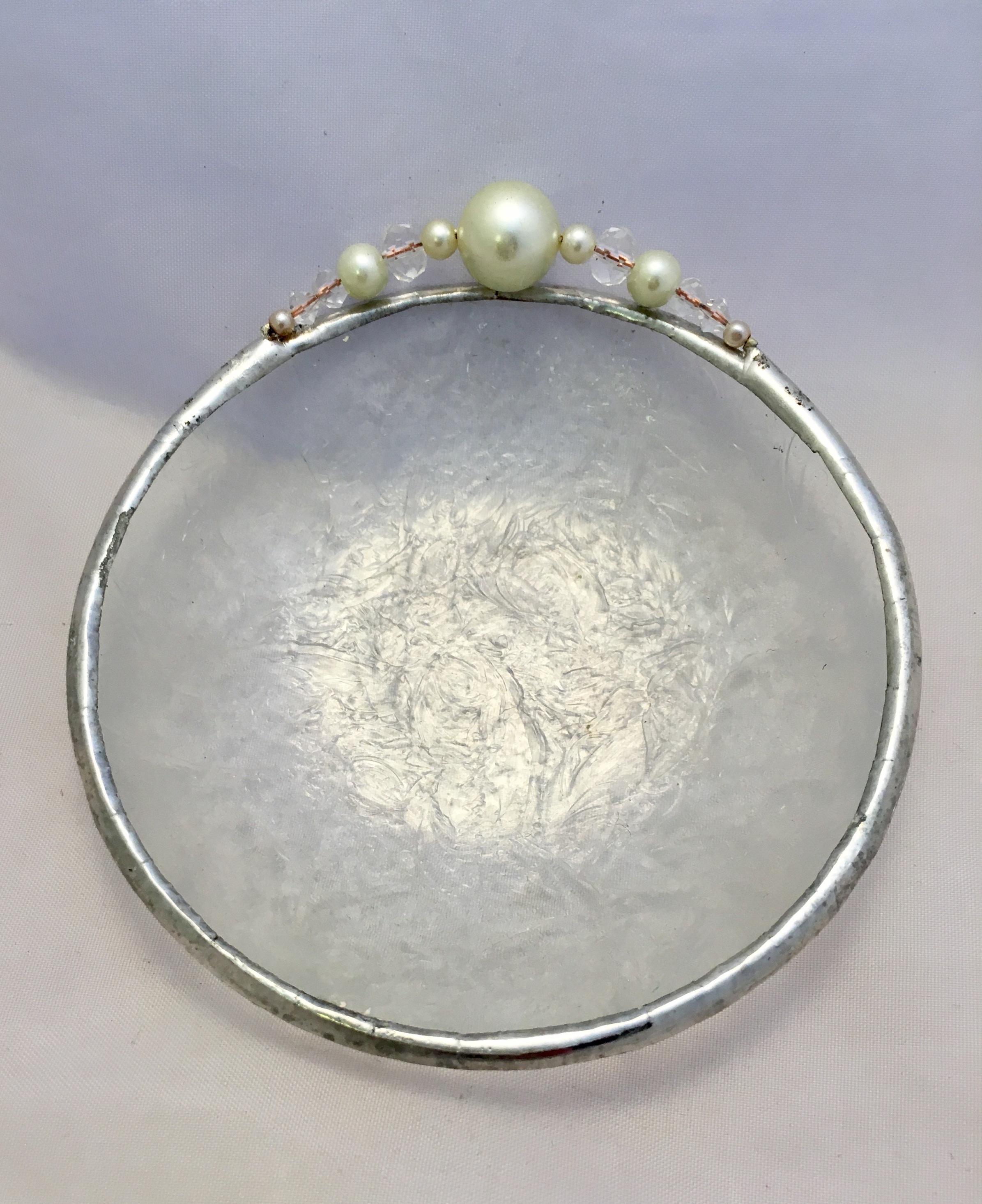 A silver plate with a white pearl on top of it.