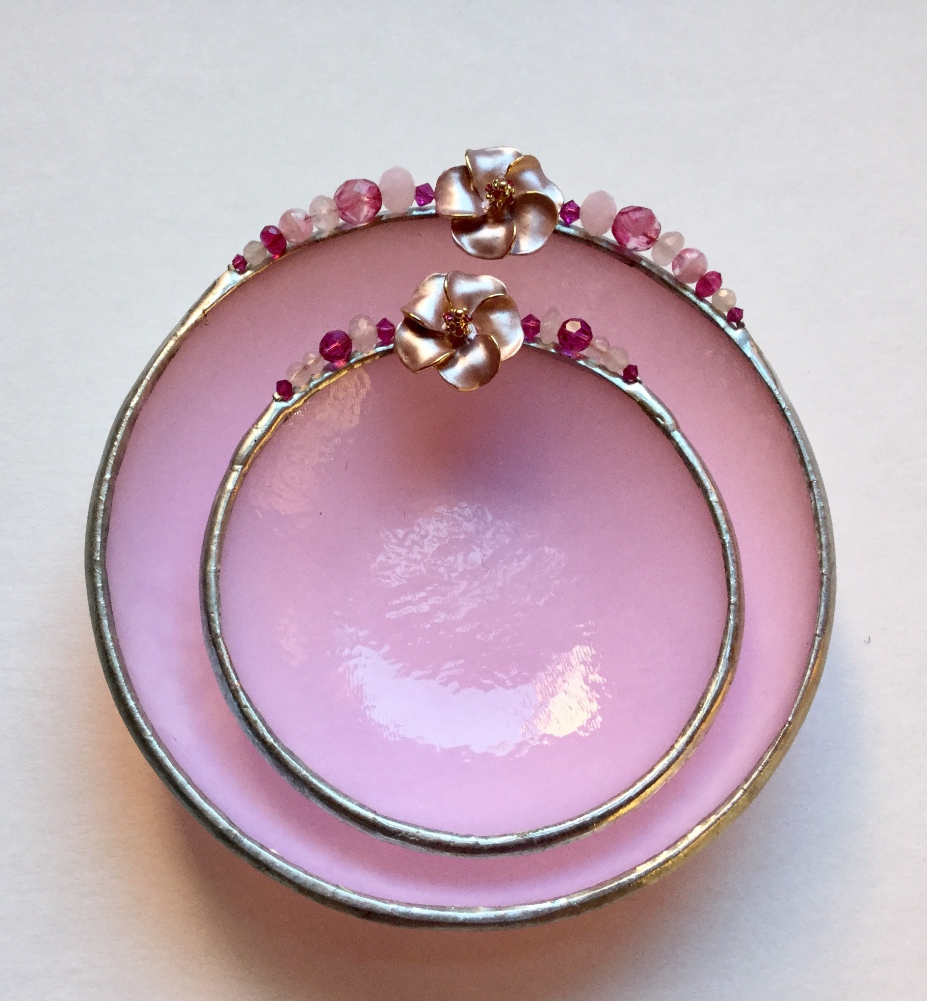 A pink bowl and plate with beads on top of it.