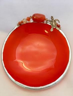 A red bowl with some orange beads on top of it