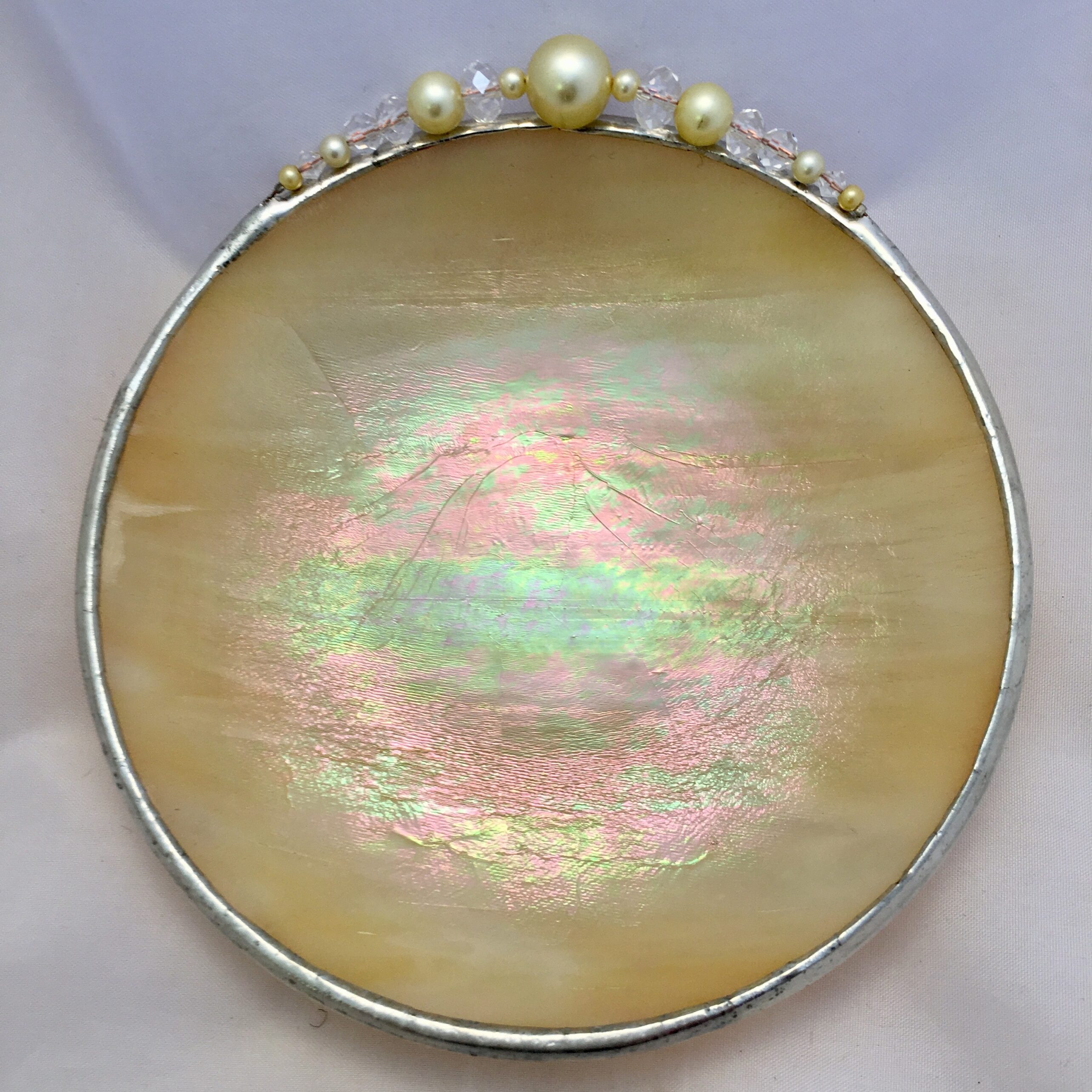 A round dish with pearls and a silver rim.