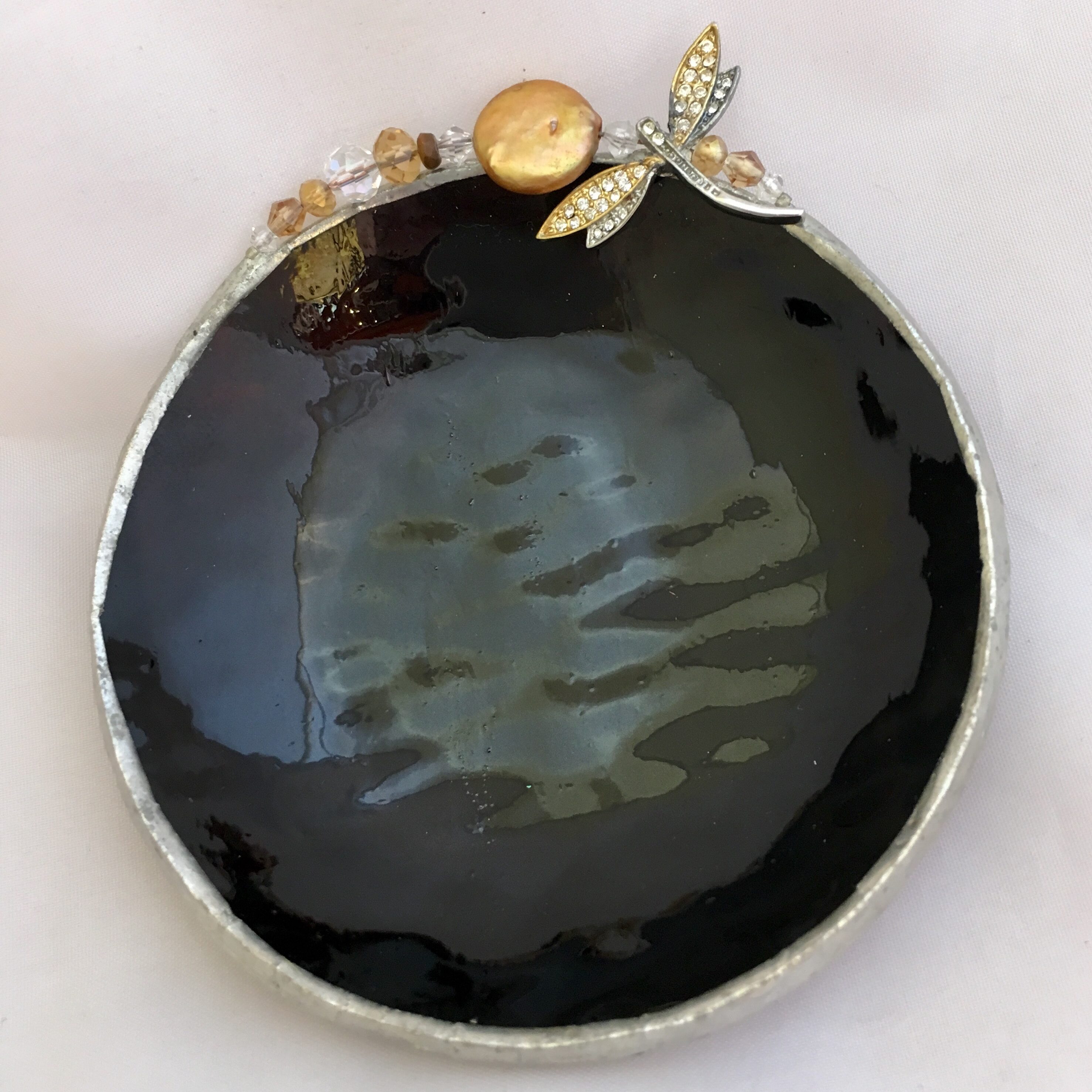 A black dish with gold accents and a bee on it.