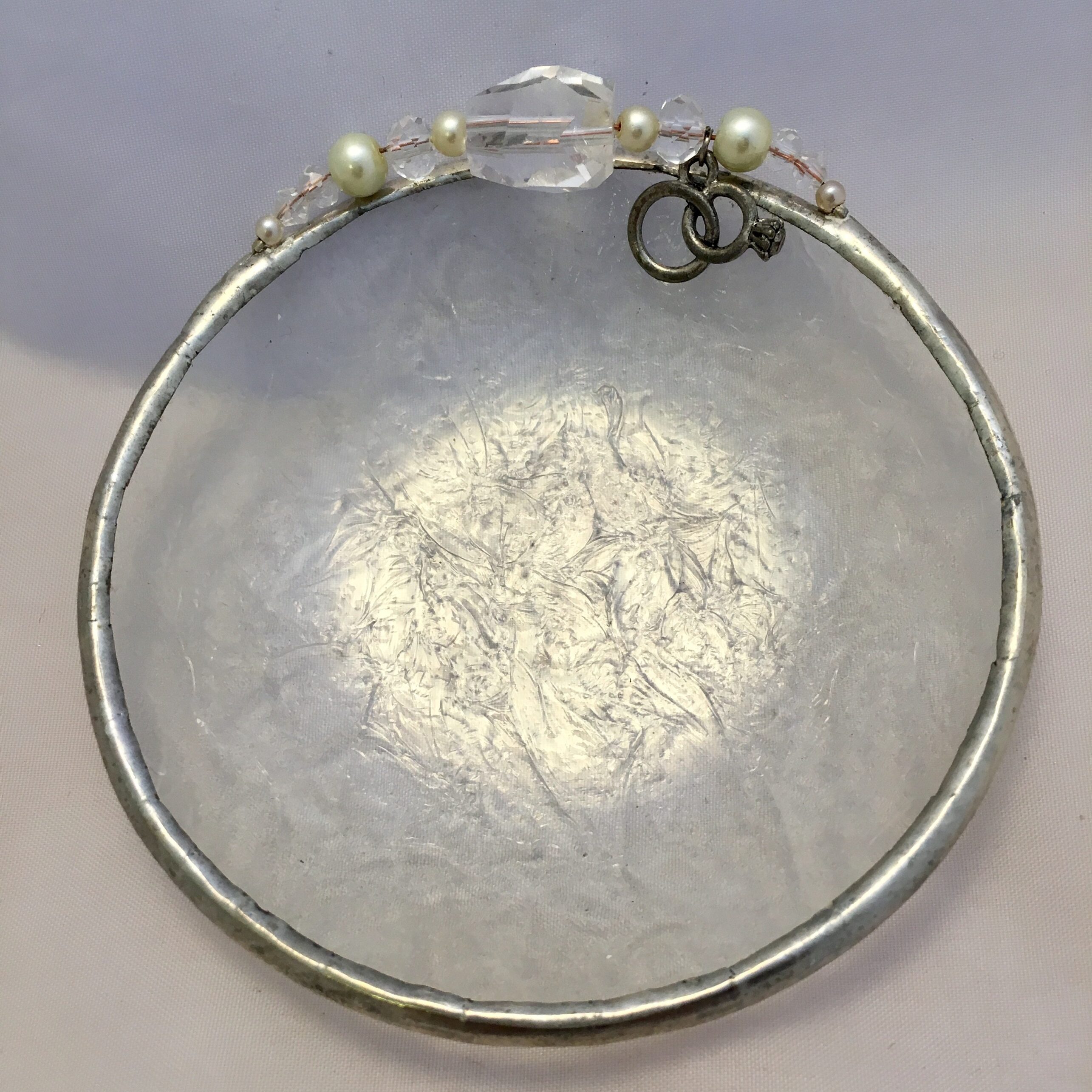 A glass bowl with some pearls and a wire