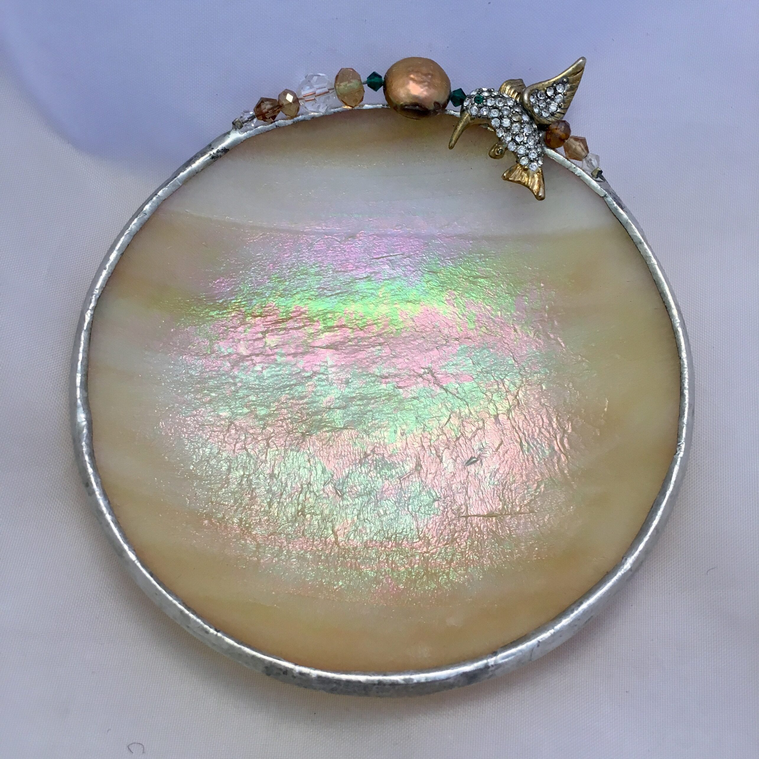 A round iridescent dish with a butterfly charm.