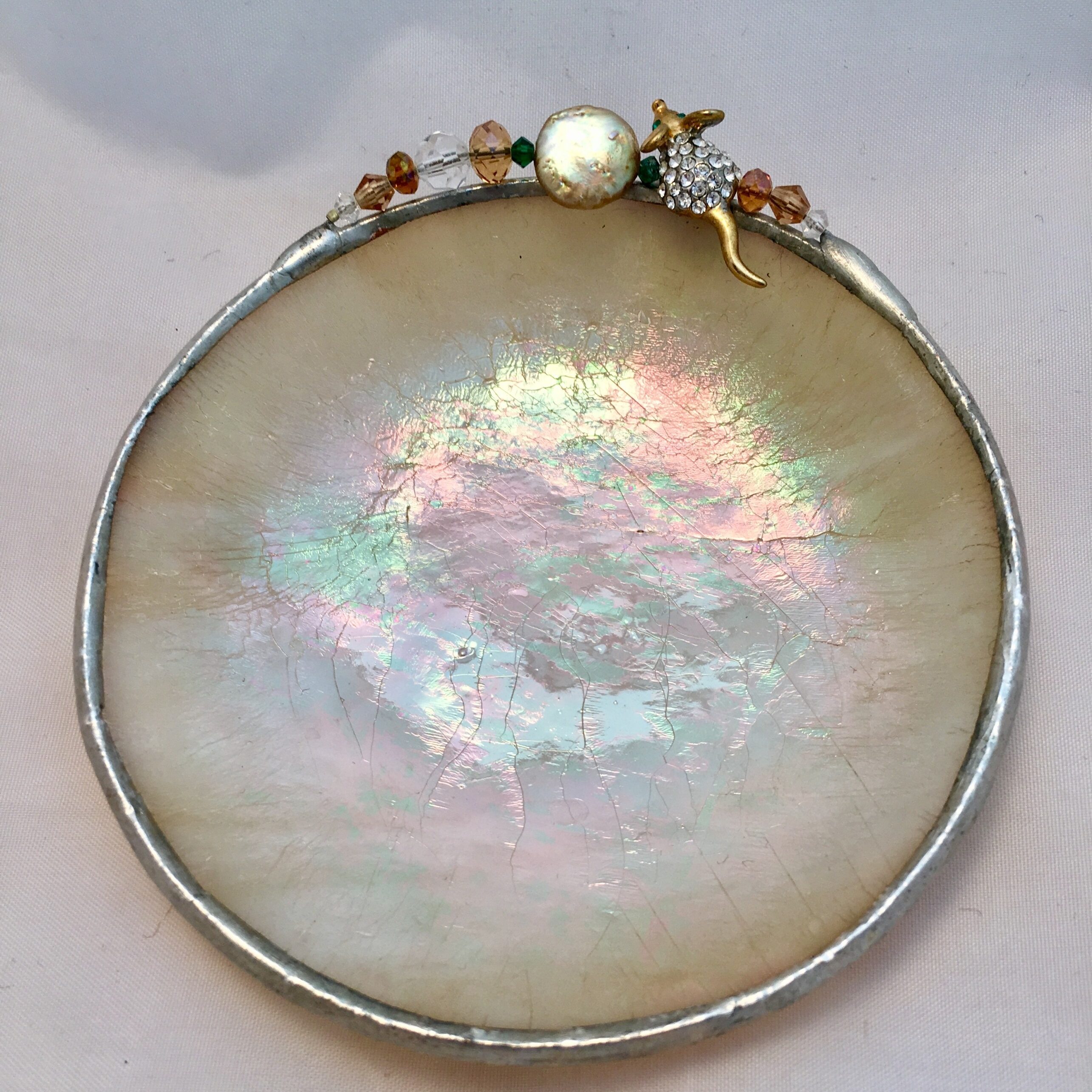 A round dish with a pearl and bead decoration.