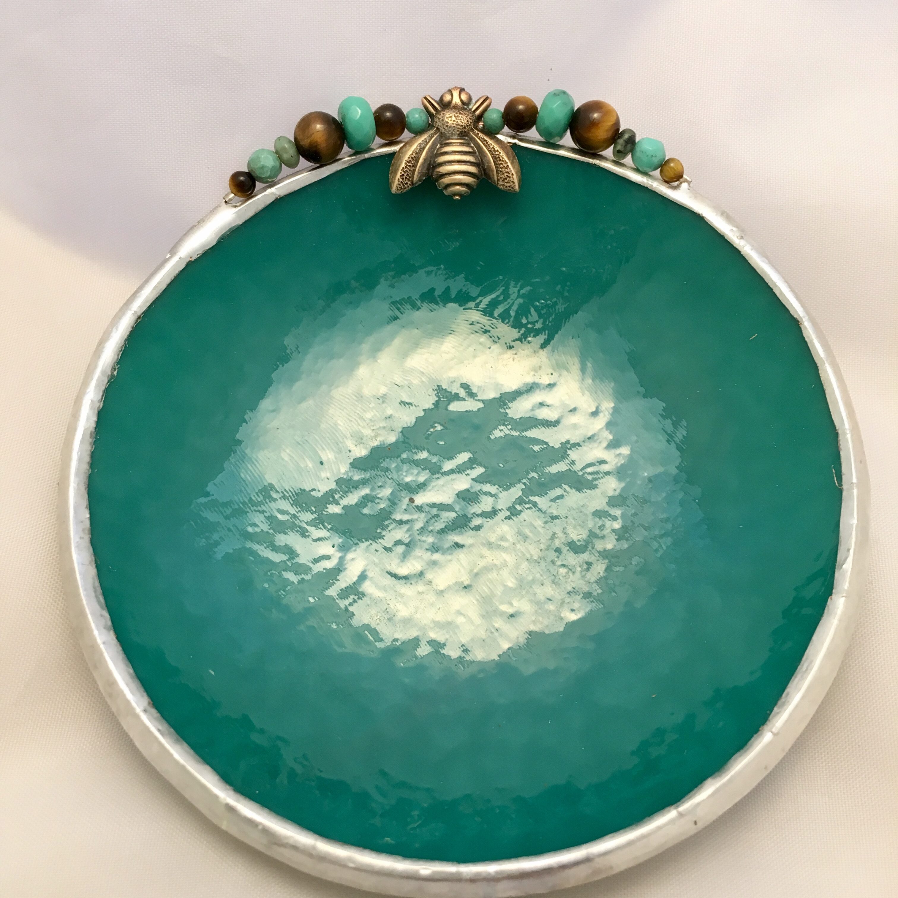 A bowl with a bee on it and some beads