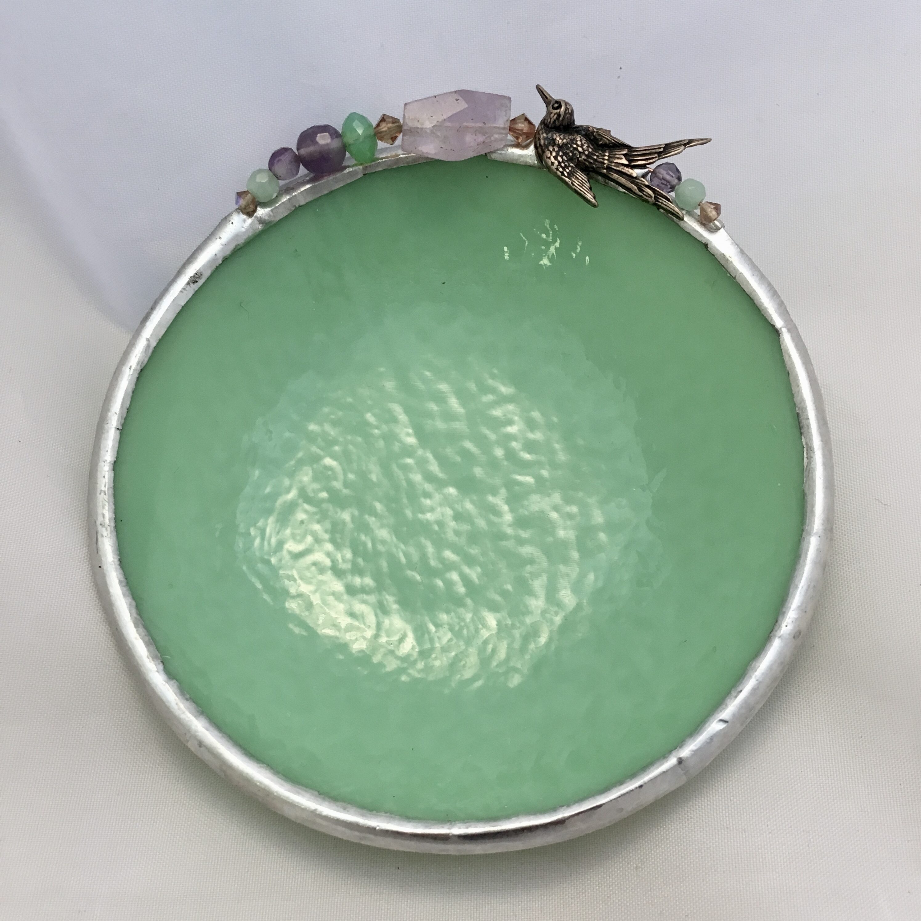 A green plate with some silver trim and a few small decorations