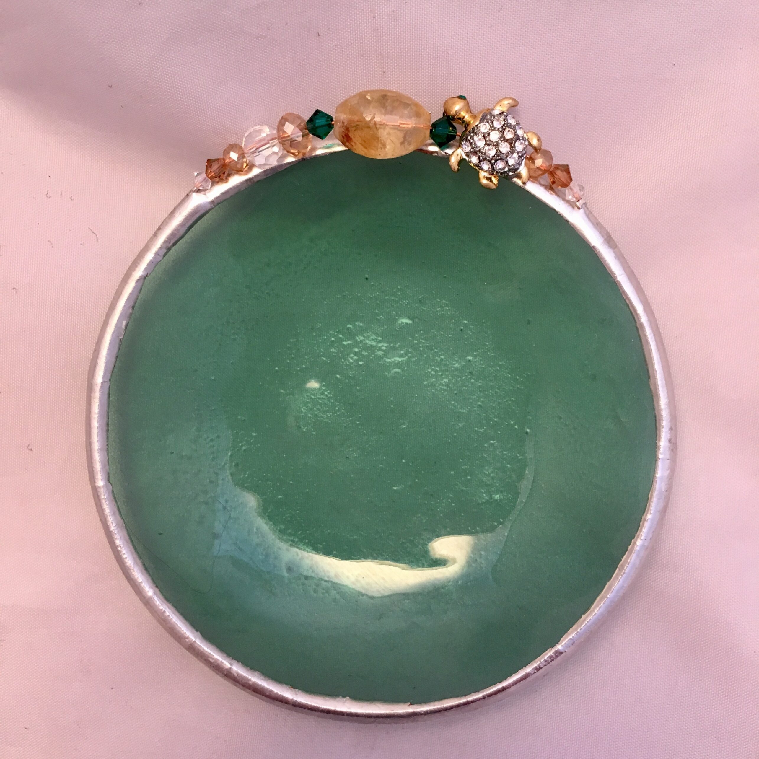 A green bowl with some orange beads on top of it