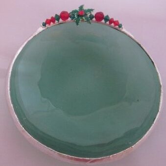 A green dish with red berries on top of it.