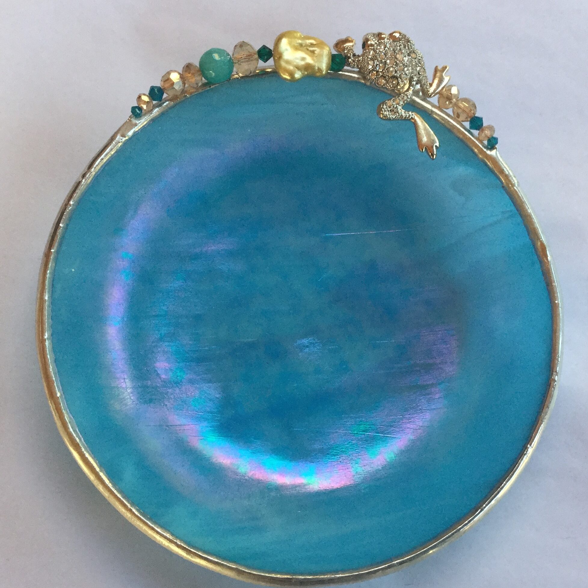 A blue dish with gold trim and some green beads