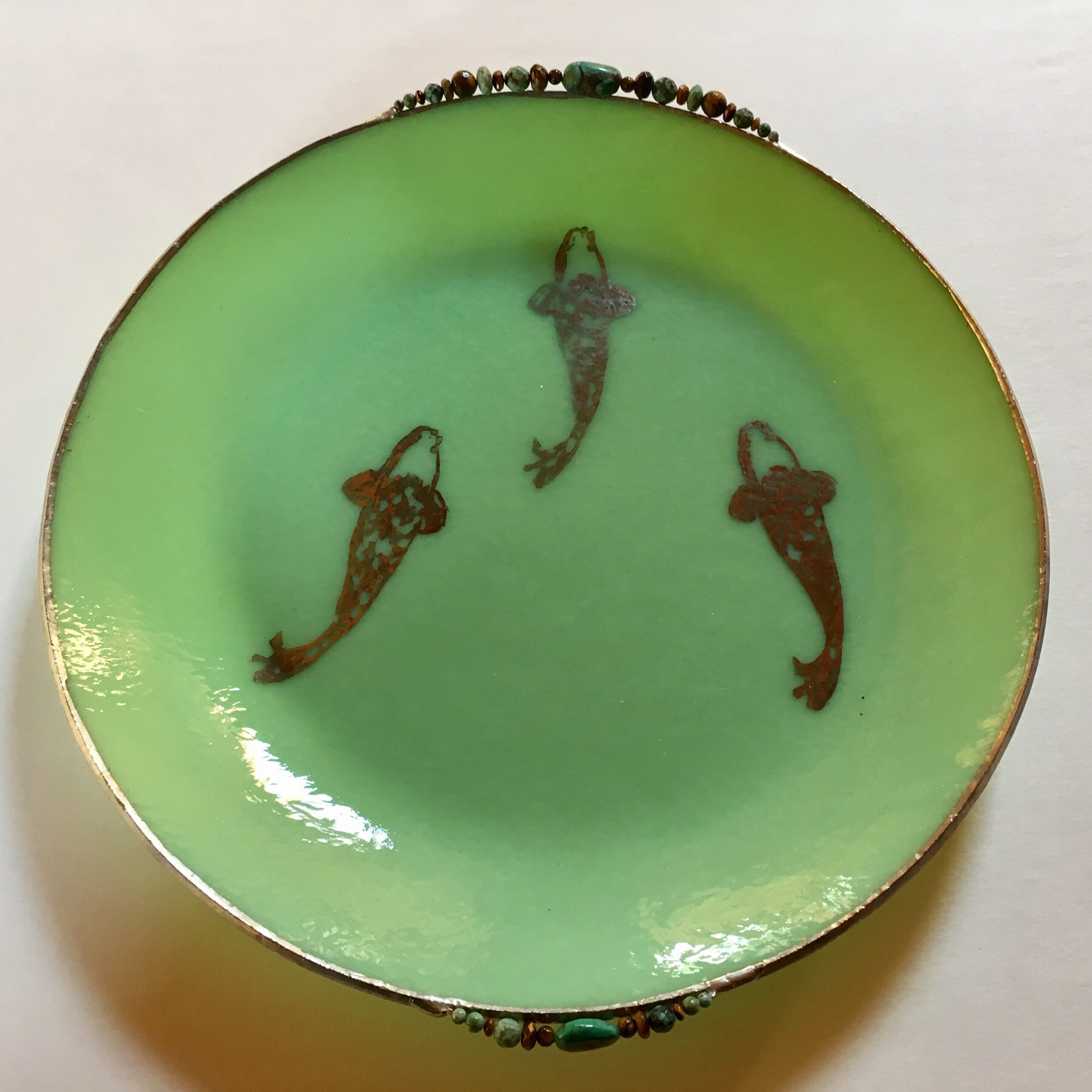 A green plate with three brown fish on it.