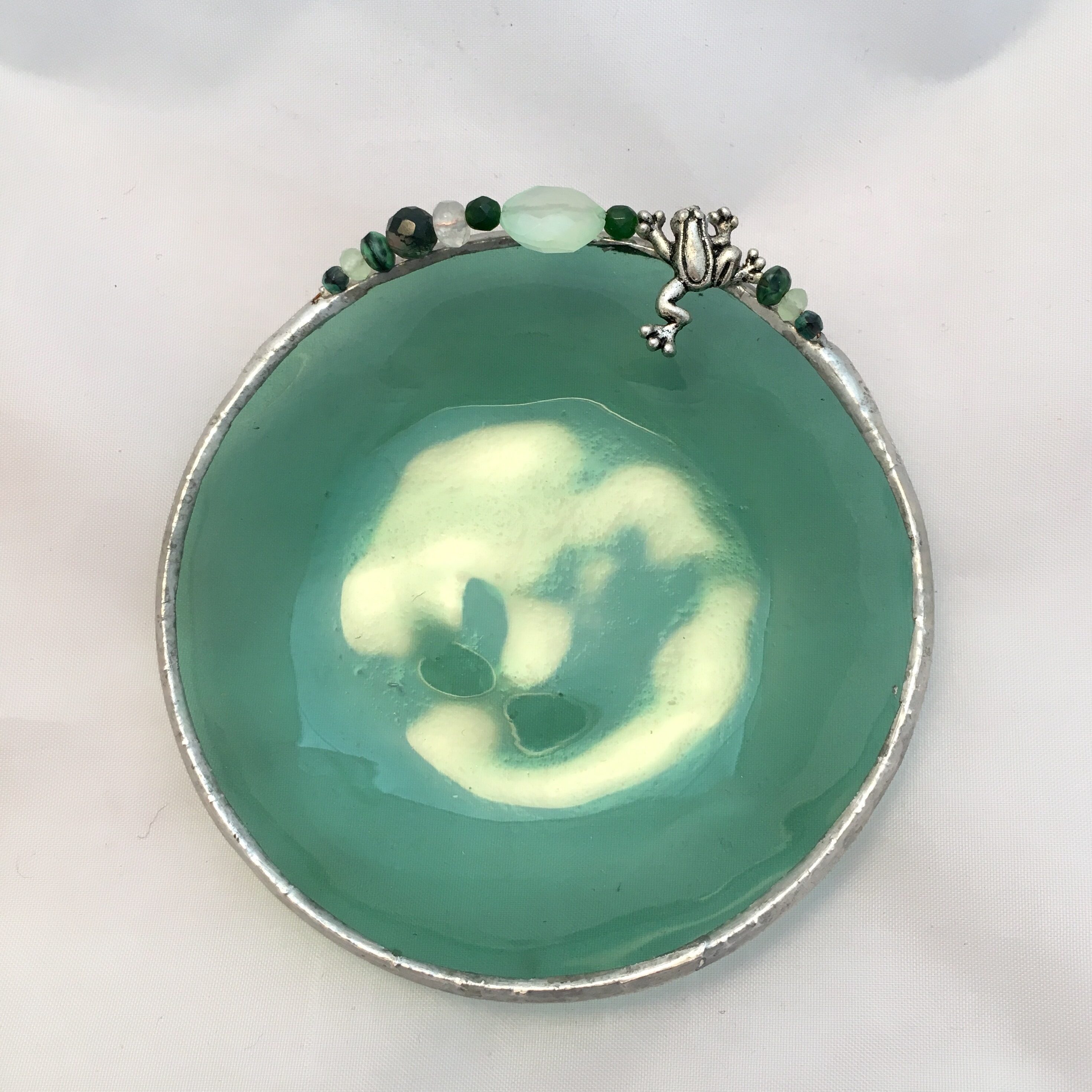 A green bowl with some white and black beads