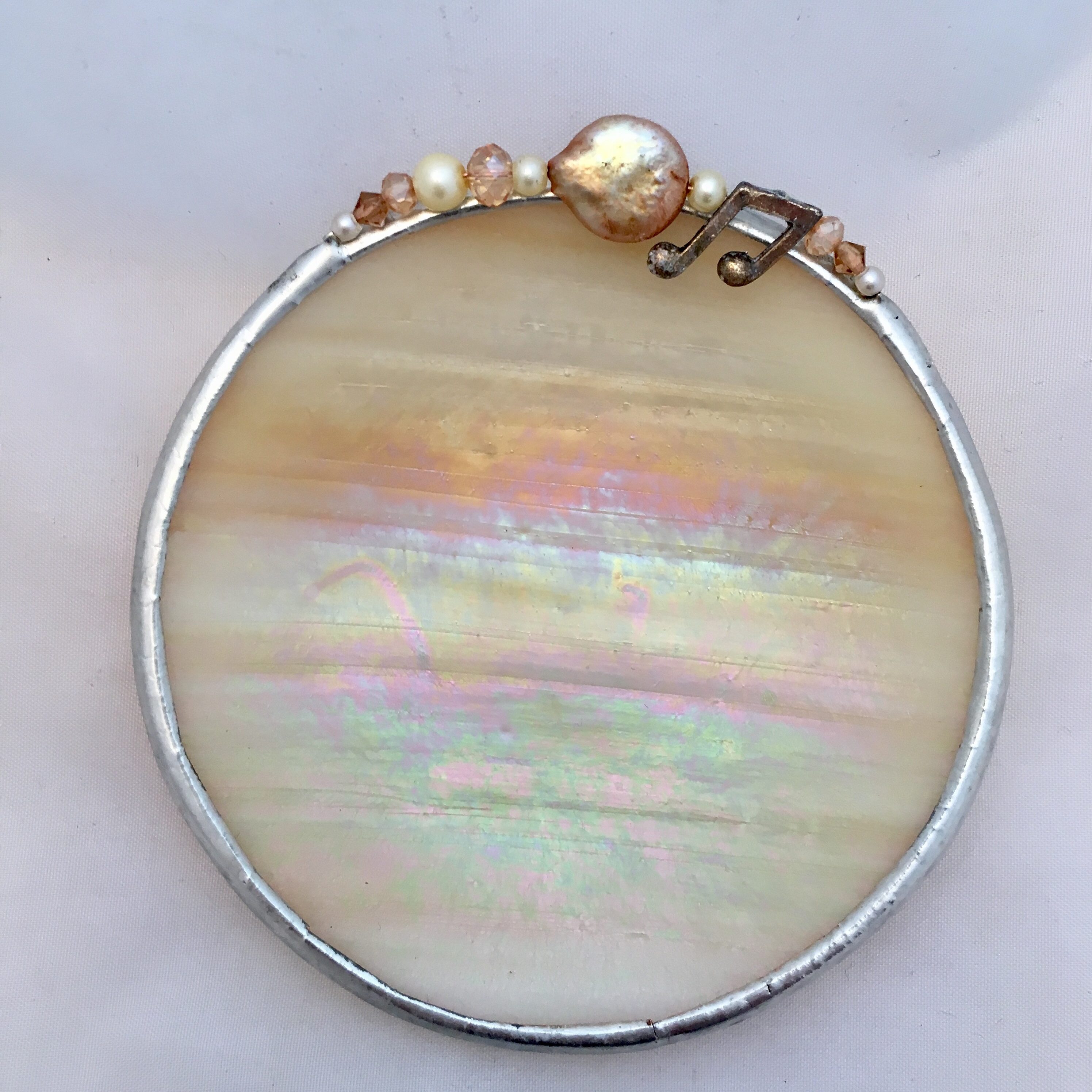 A round white and gold colored frame with pearls.