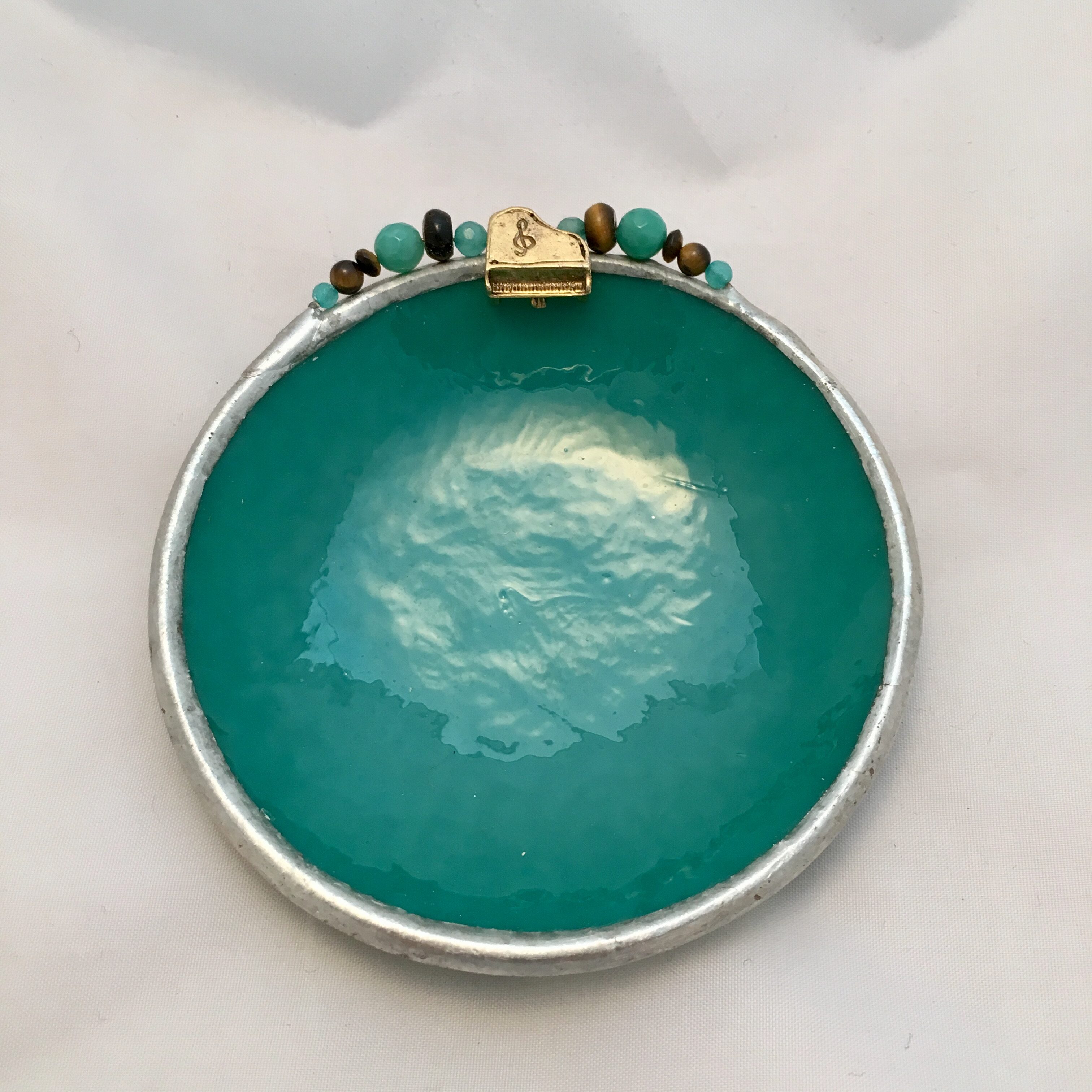 A green bowl with beads on top of it.