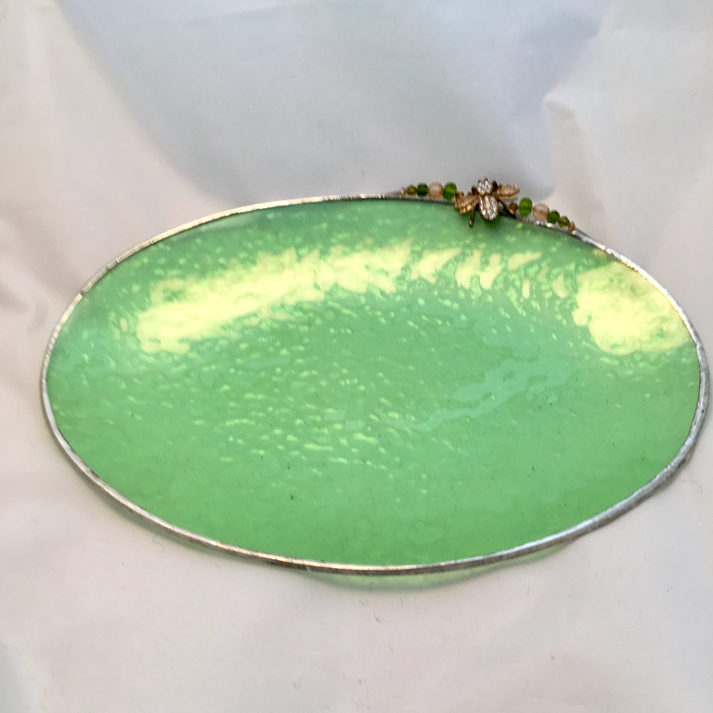 A green plate with a silver rim on top of a table.