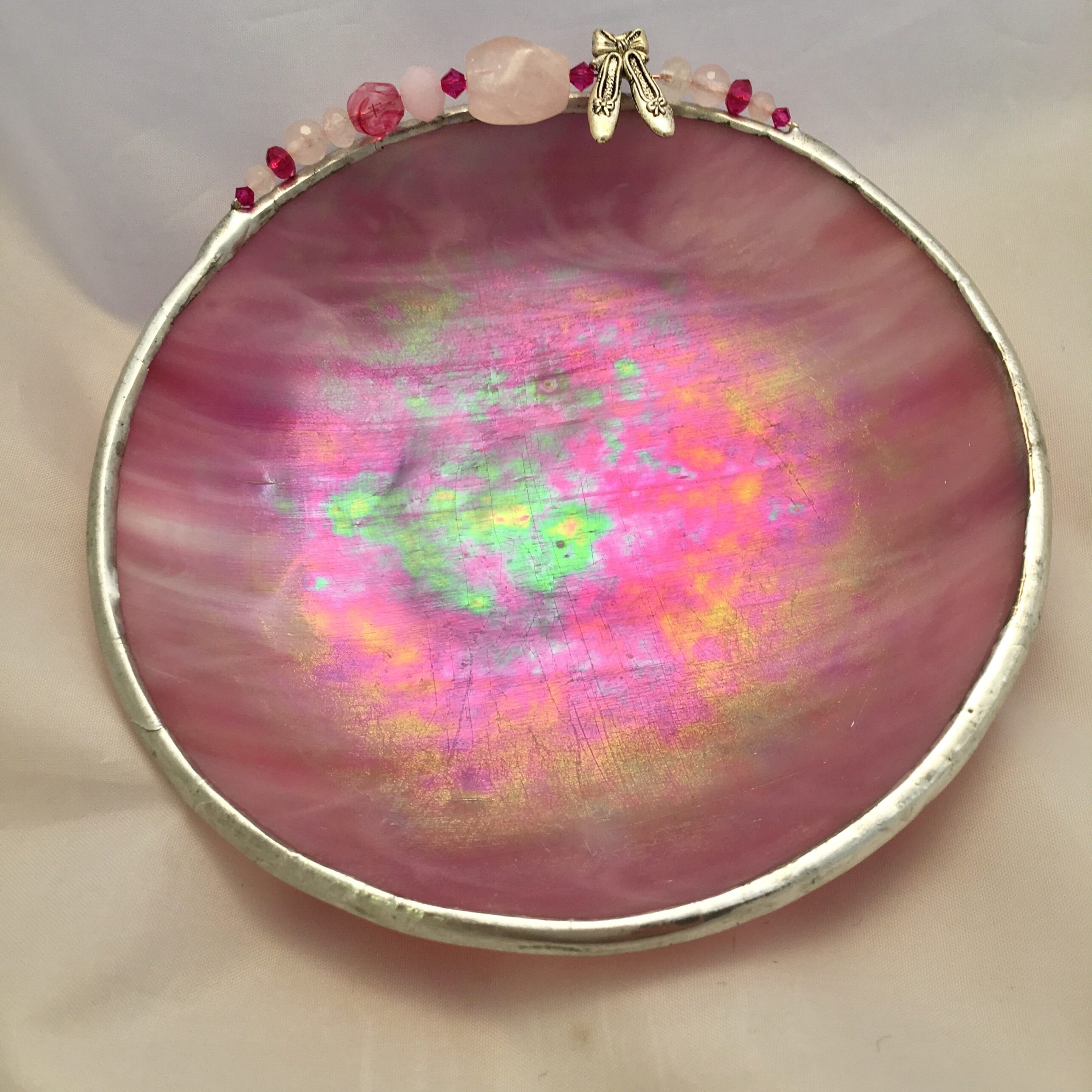 A pink bowl with a rose quartz bead and a silver rim.