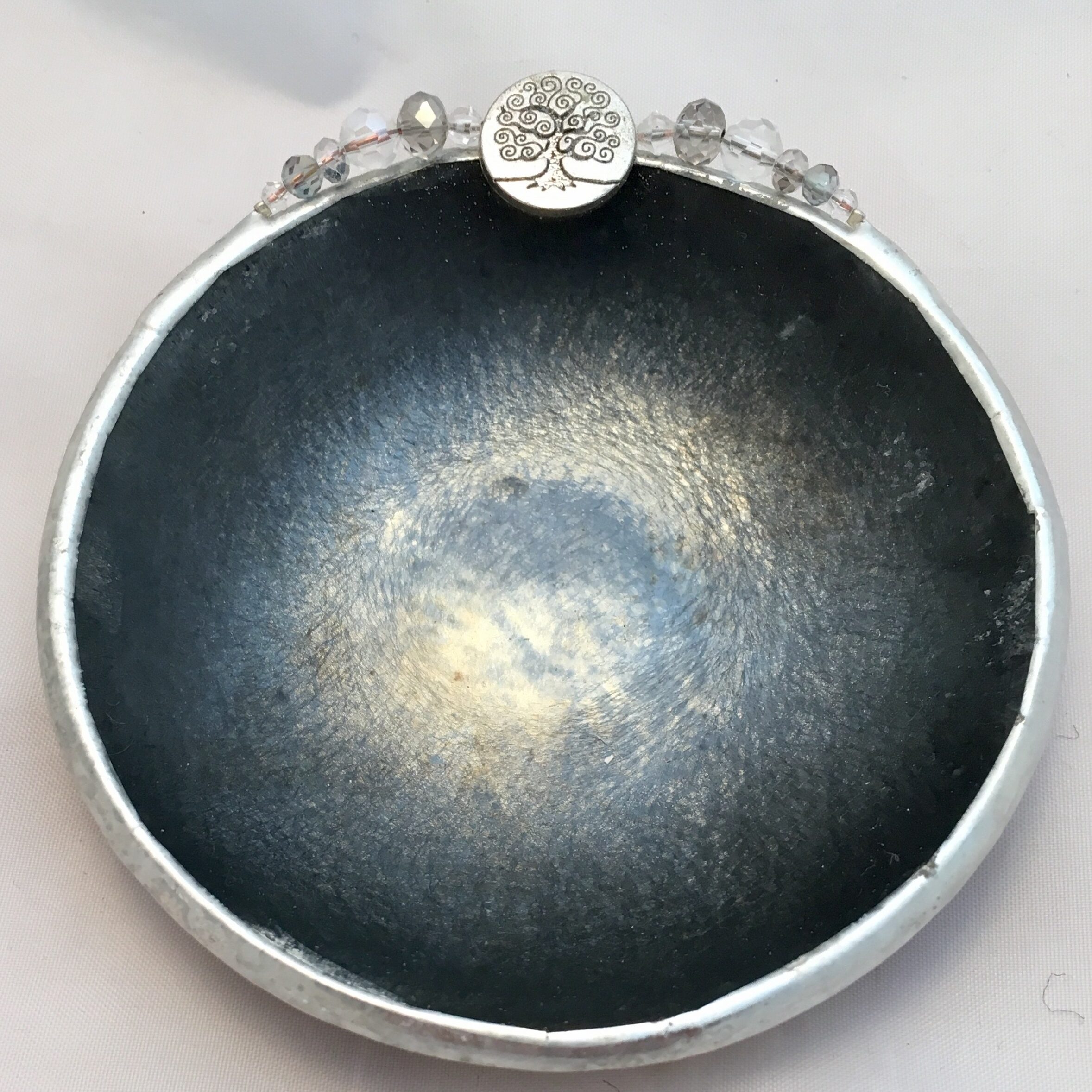 A black bowl with silver rim and a flower on top.