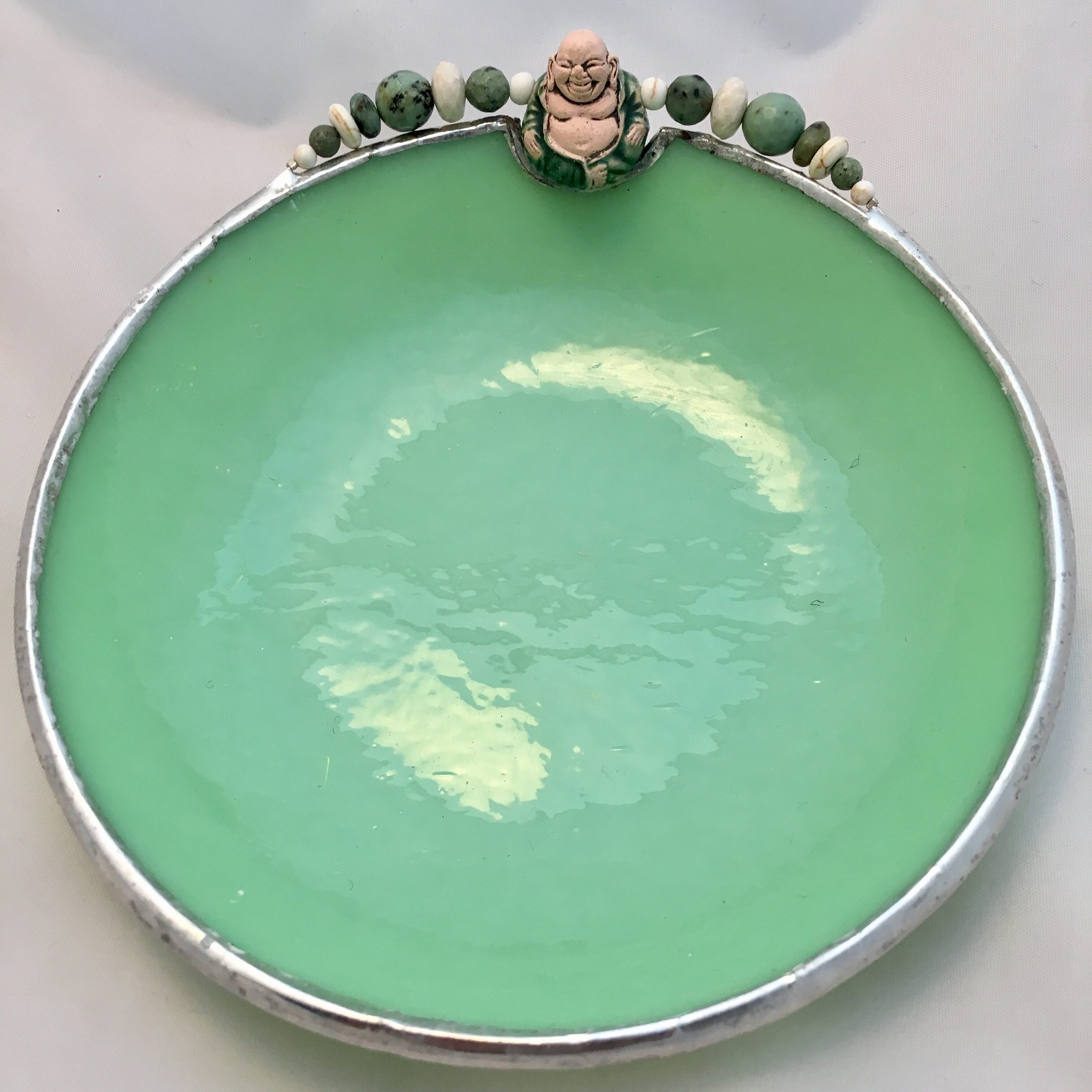 A green plate with some white and blue beads