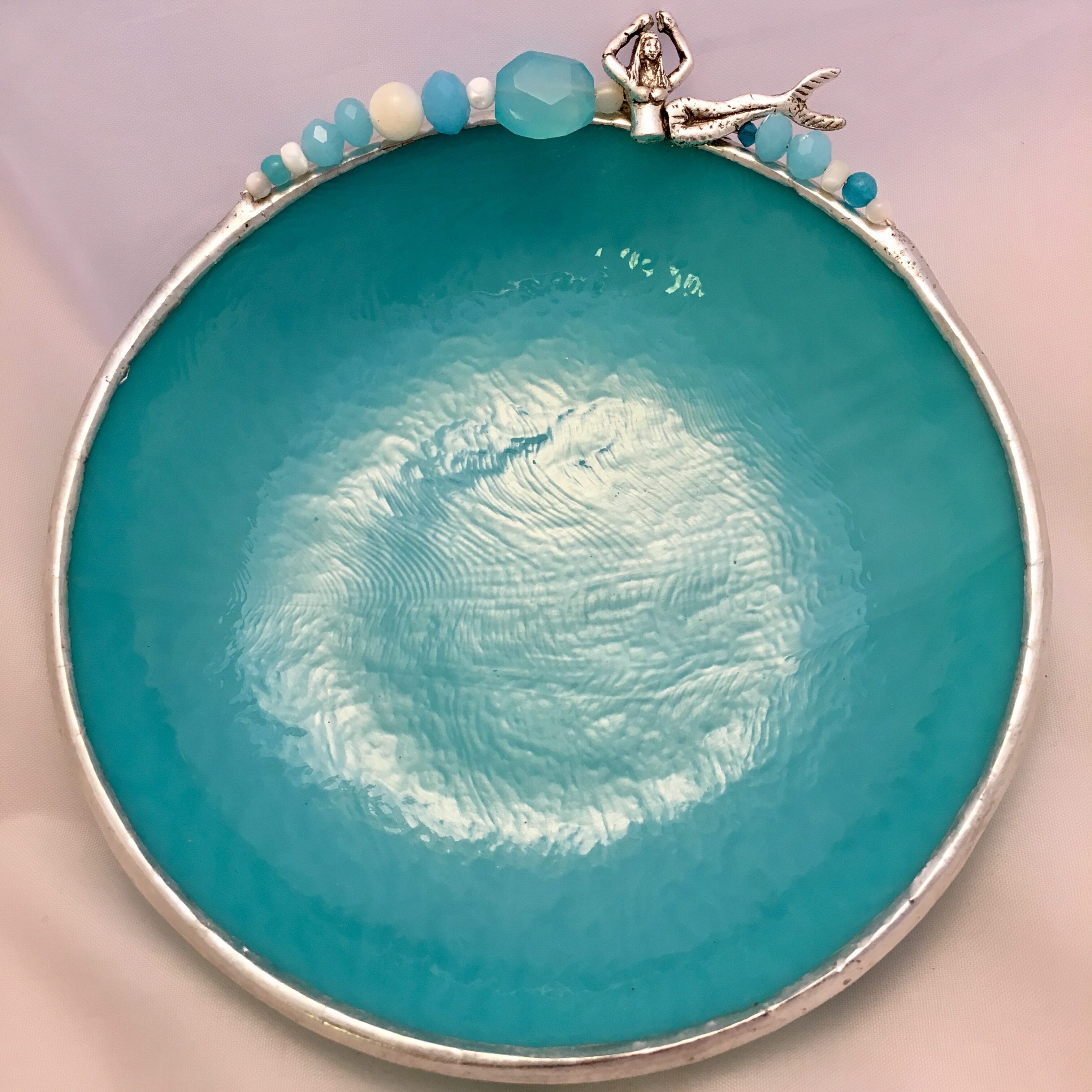 A blue bowl with a silver rim and a bird charm.