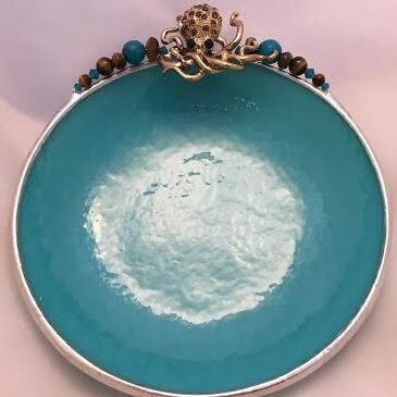 A bowl with turquoise glaze and beads on top of it.