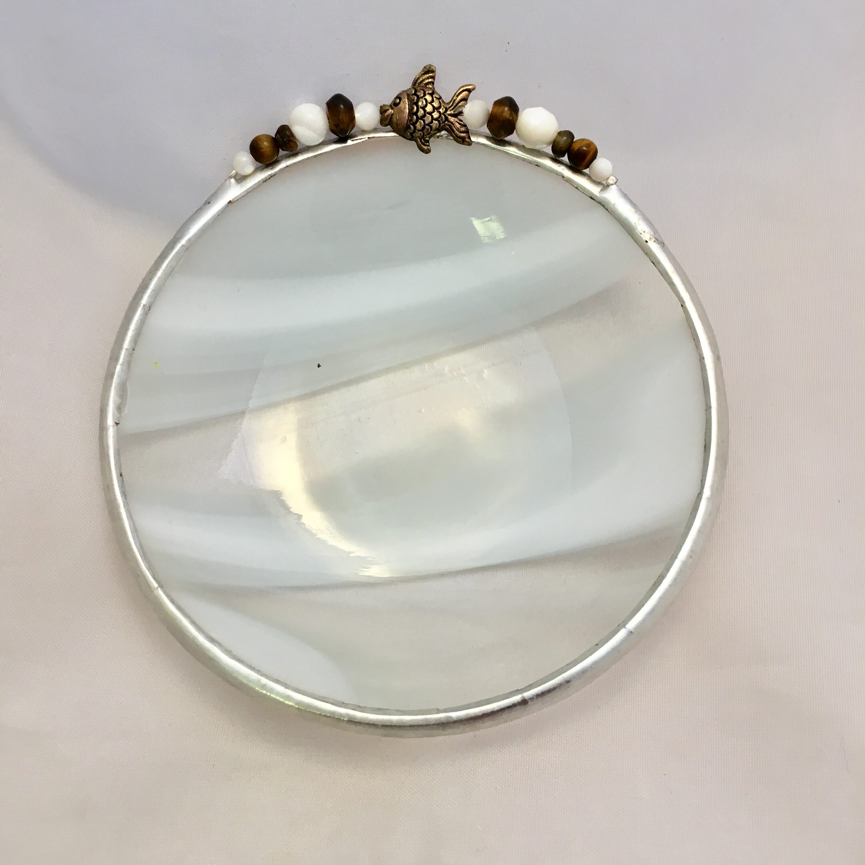 A round mirror with pearls and a star on it.