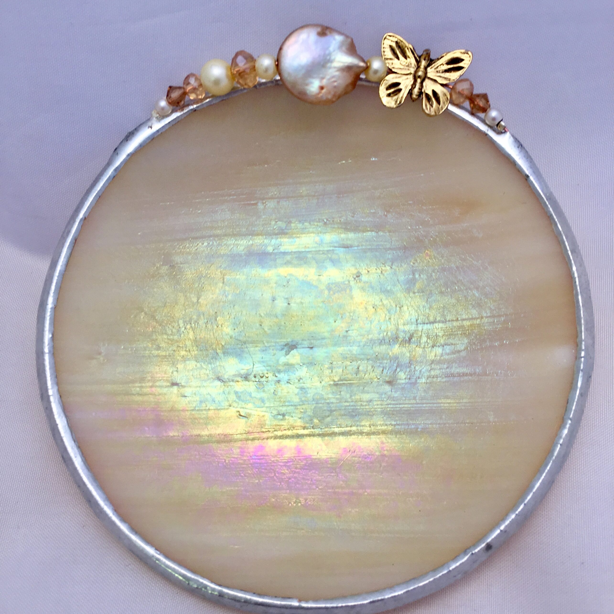 A round mirror with pearls and gold accents.