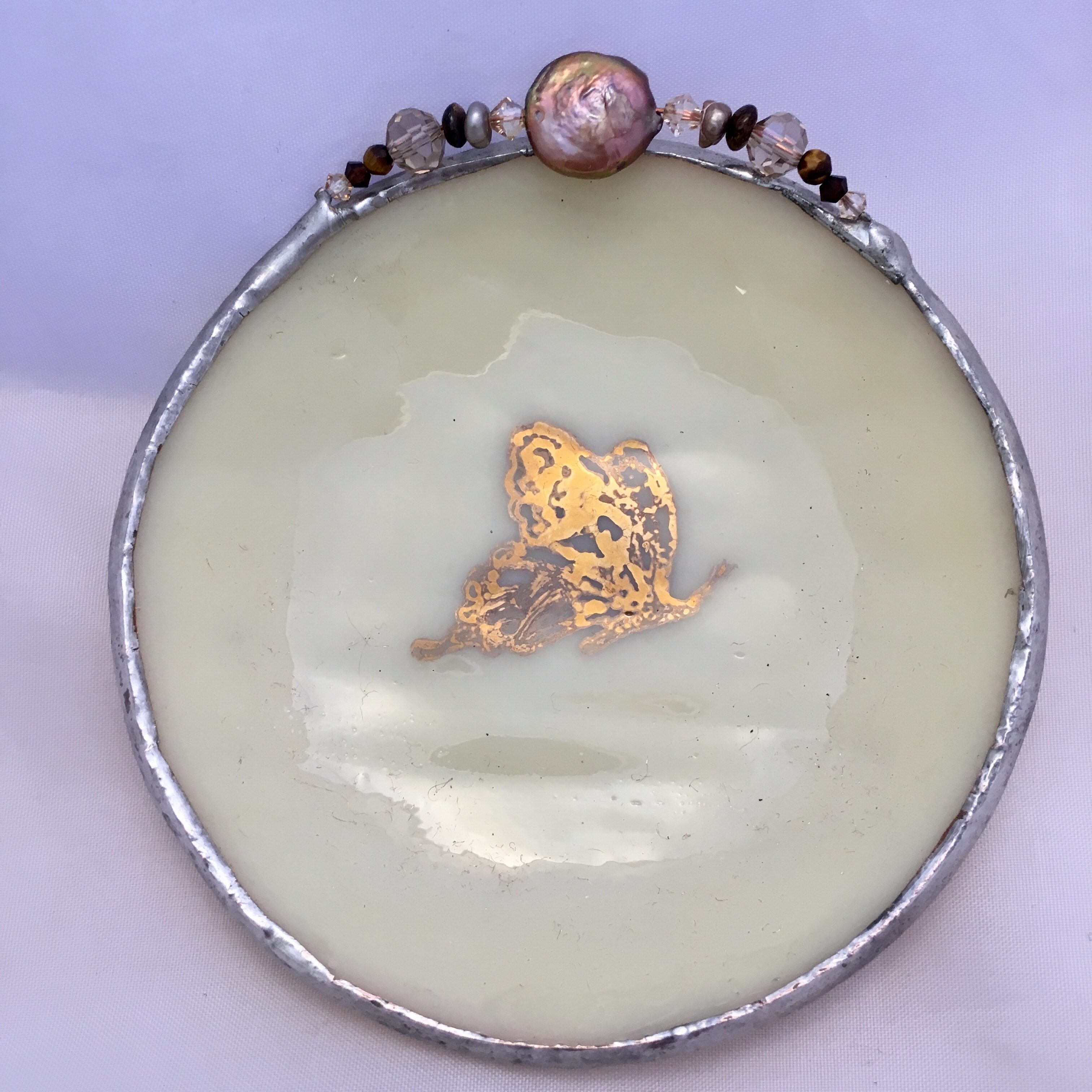 A round glass plate with gold leaf and flowers.