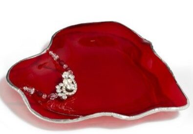 A red glass dish with silver trim and a diamond shaped design.