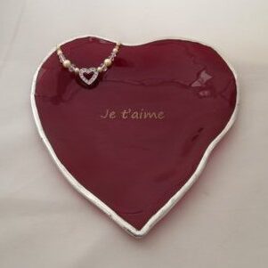 A red heart shaped dish with the words " je t ' aime ".