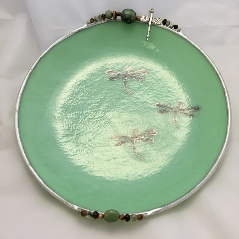 A green plate with dragonflies on it