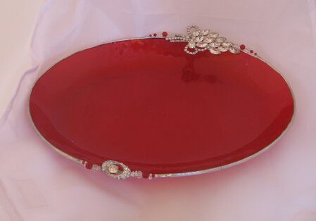 A red plate with silver handles and a decorative design.